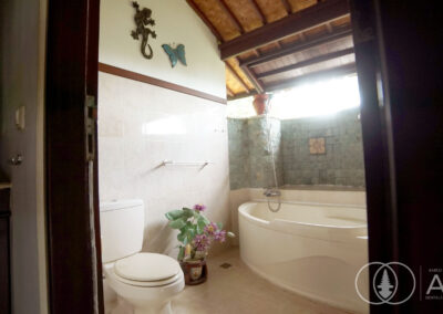 enSuite bathroom in a Balinese villa with bathtub and green tiled walls.