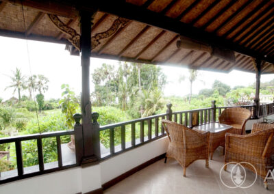 View of tropical gardens from 2nd floor balcony with seating area of a beachfront villa in Amed, Bali