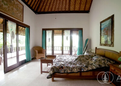 Wooden bed-frame and wooden sliding doos in bedroom of a villa in Amed, Bali