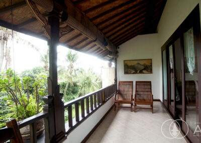 Balcony with wooden chairs and doors leading out from the upper floor bedroom of a villa in Amed, Bali.