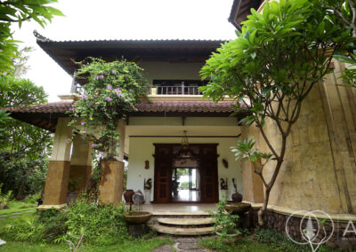 Traditional style Balinese villa with tropical trees in lush garden