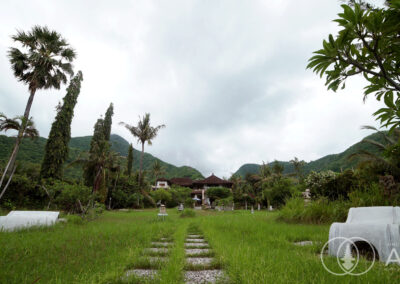 Long garden looking back toward a large Balinese villa with Amed's tropical hills in background