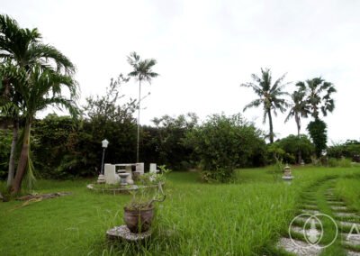 Garden with stone furniture seating area and a path leading towards the beach