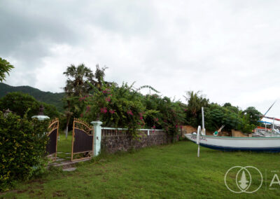 Boats settled near the beach with a access gate leading to a large beachfront villa in Amed, Bali.