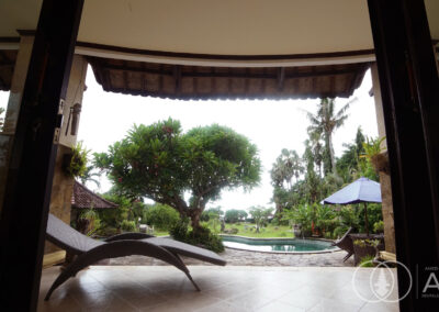 View from an outdoor villa terrace through teak columns looking at the swimming pool