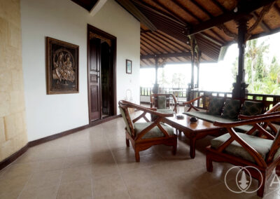 Seating area with teak wooden chairs and table on a balcony in a traditional Balinese villa in Amed.