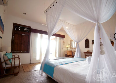 Bed with netting facing open doors leading onto a garden in Amed, Bali.