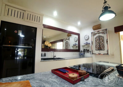 Kitchen island with cooker, oven and large wooden framed mirror.