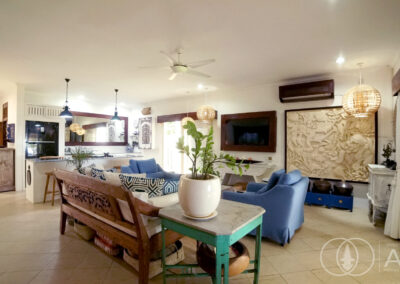 Living room sofas with wall mounted TV and traditional Balinese wooden wall art