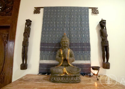 Statue of Buddah and traditional Balinese wooden figures hanging from the wall