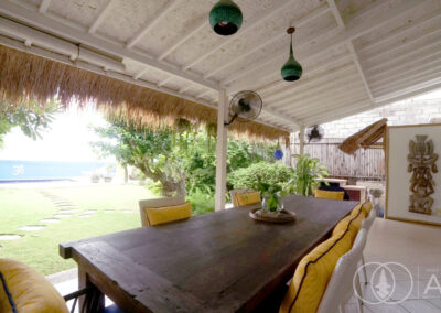 Dining table under covered terrace overlooking the garden of a beach front house in Amed